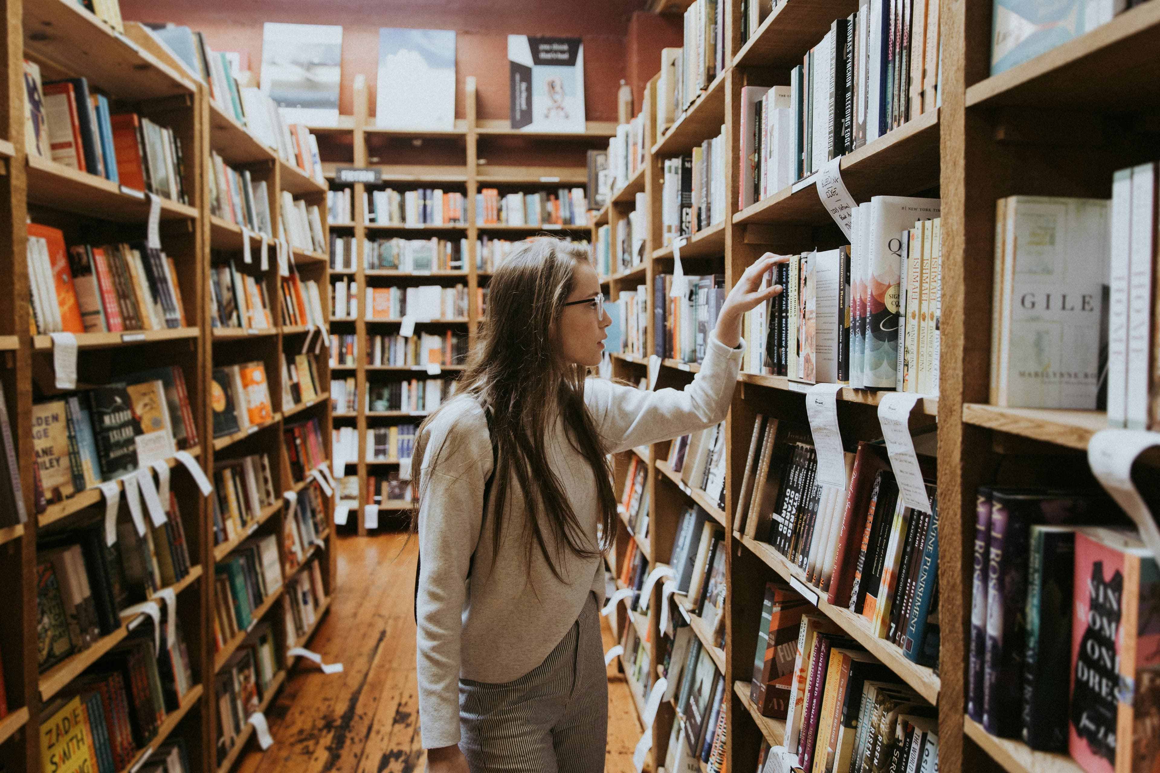 Студентка держит книгу среди книжных полок