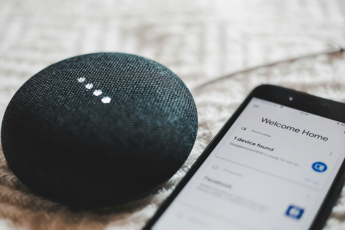Включённая умная колонка Google Home Mini рядом со смартфоном
