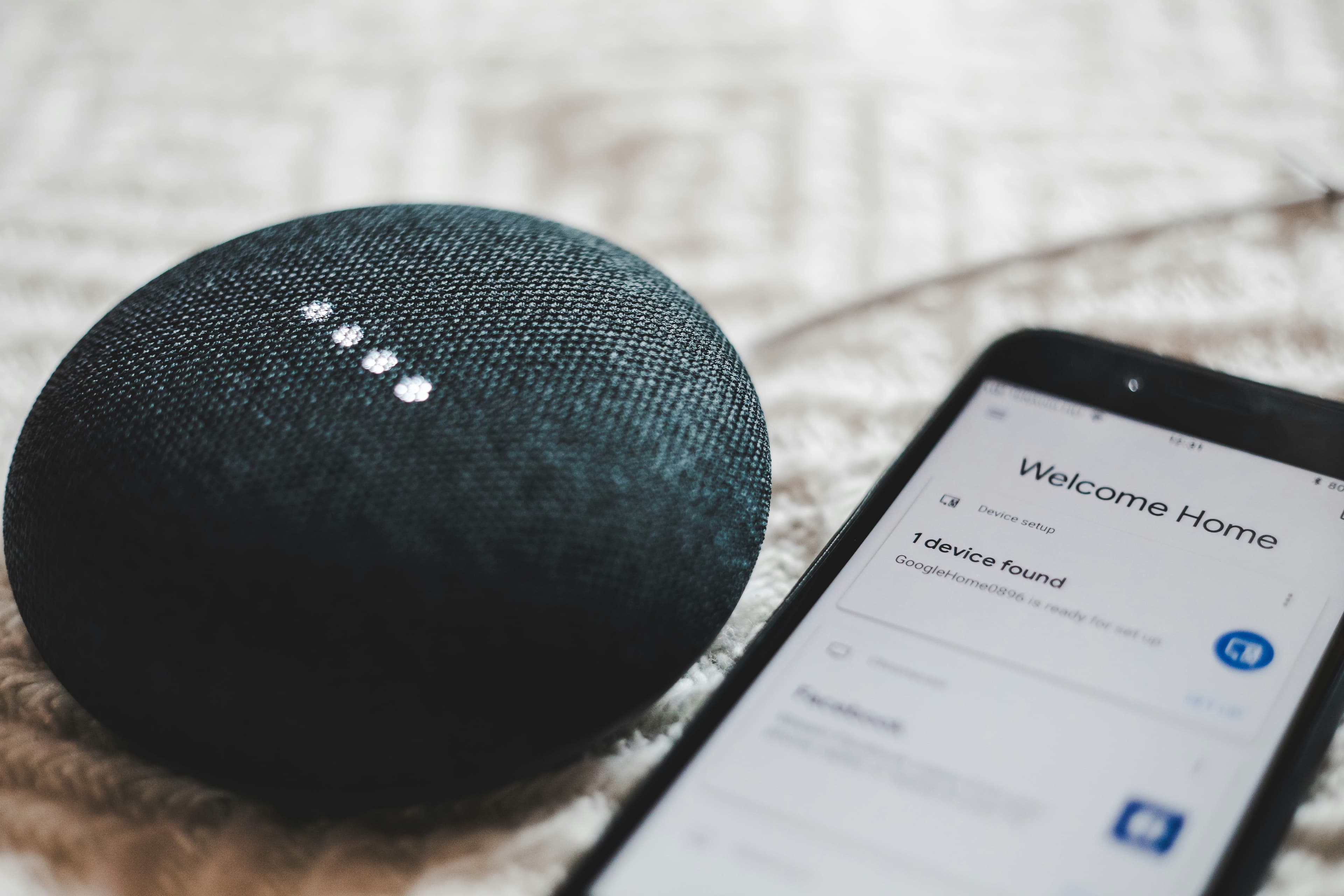 Включённая умная колонка Google Home Mini рядом со смартфоном