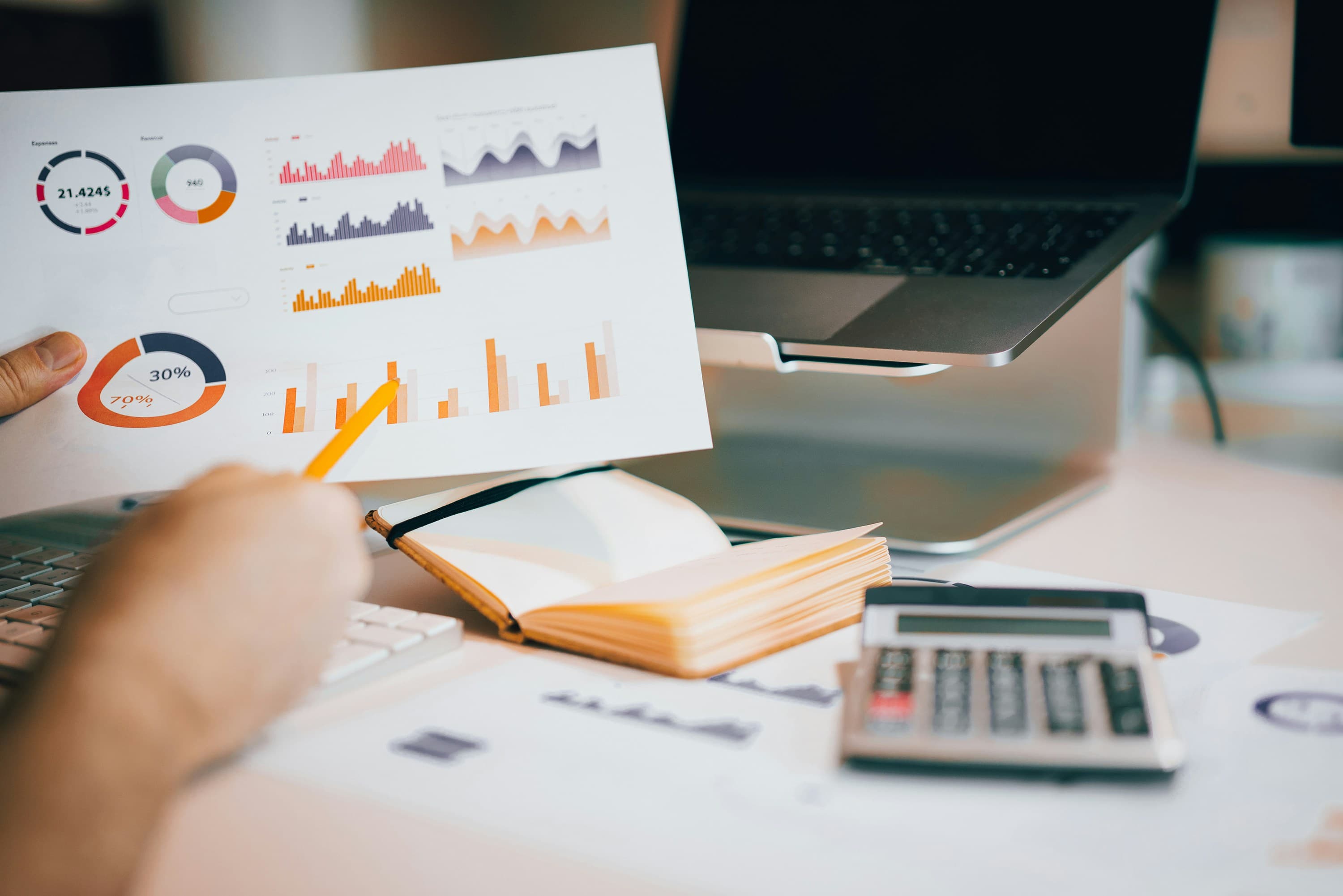 Человек держит документ над ноутбуком, изучение бумаг
